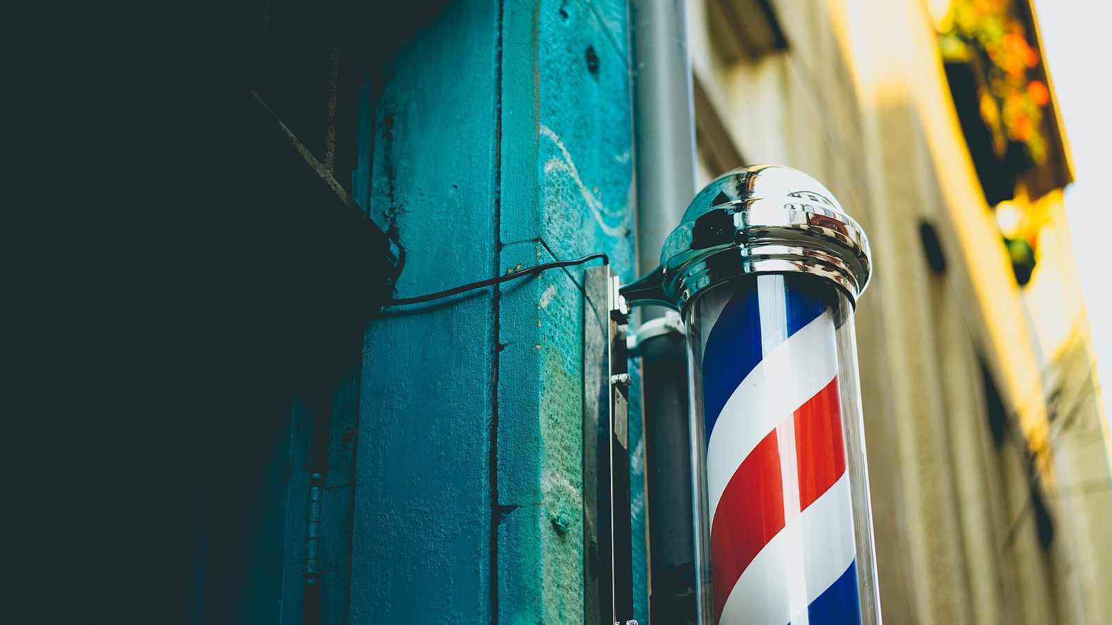 L’insegna a strisce bianche, rosse e blu fuori da una barberia