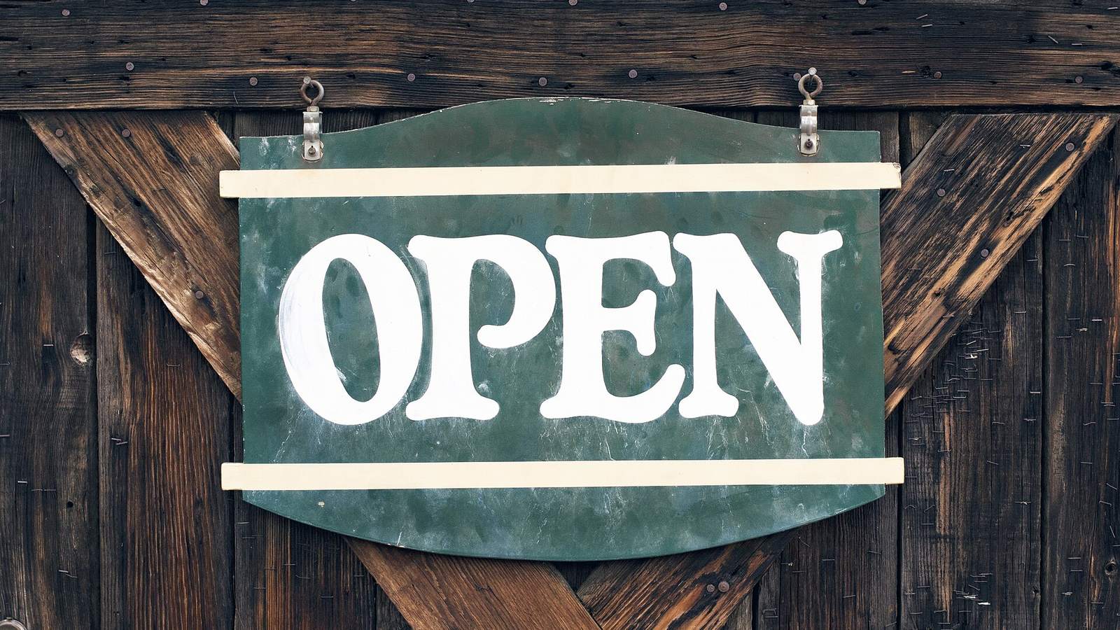 Un cartello «Open» appeso a una porta di legno